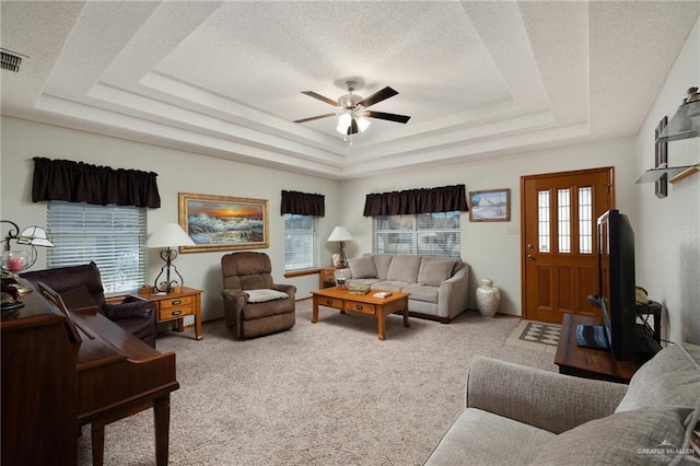 carpeted living room featuring ceiling fan, a tray ceiling, and a textured ceiling