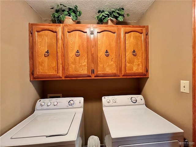 laundry area with cabinets, washing machine and dryer, and a textured ceiling