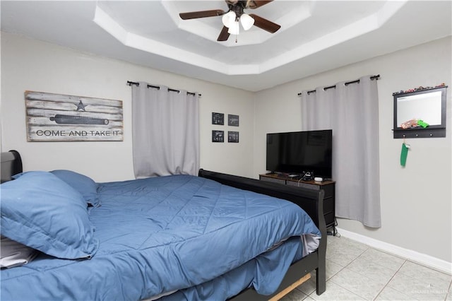 tiled bedroom with a tray ceiling and ceiling fan