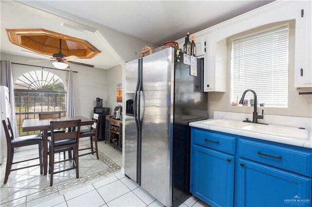 kitchen with stainless steel refrigerator with ice dispenser, blue cabinets, ceiling fan, sink, and light tile patterned floors