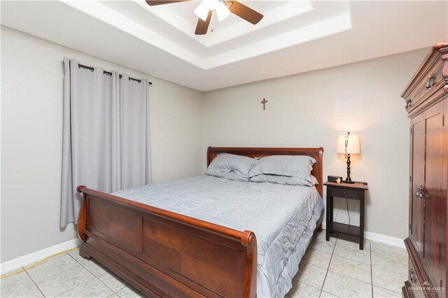 bedroom featuring ceiling fan, light tile patterned flooring, and a raised ceiling