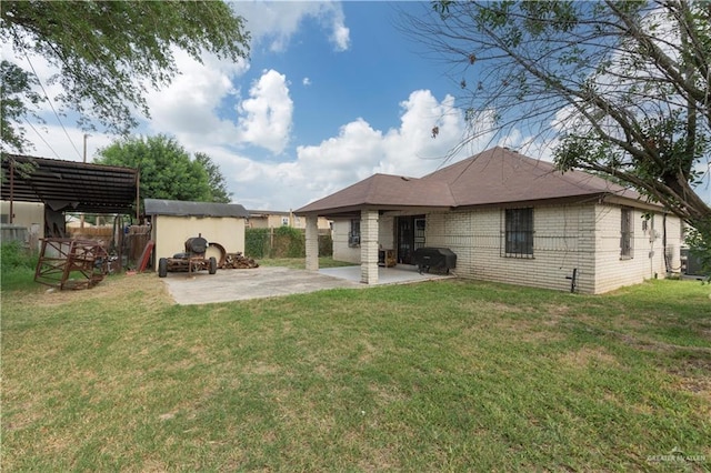 rear view of property with a yard, an outbuilding, and a patio