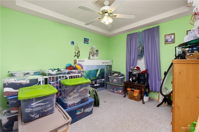 bedroom featuring a textured ceiling, carpet floors, a raised ceiling, and ceiling fan