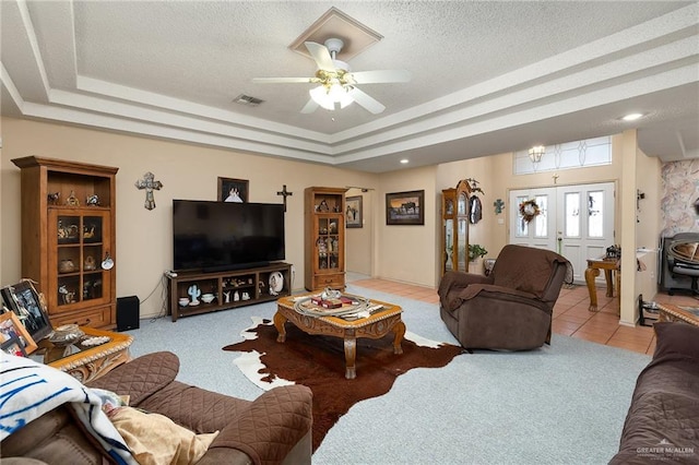 living room featuring a textured ceiling, a tray ceiling, ceiling fan, and light tile patterned flooring