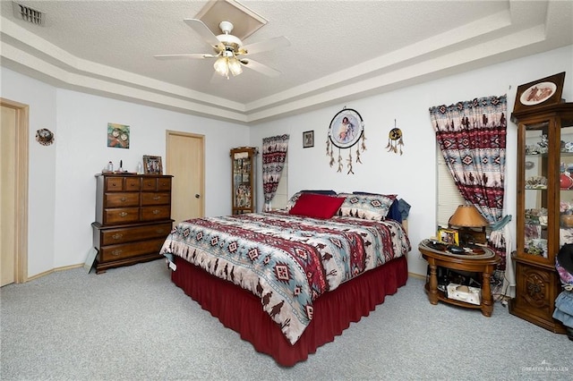 bedroom featuring a tray ceiling, ceiling fan, carpet floors, and a textured ceiling