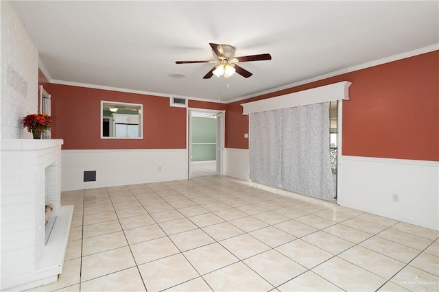 tiled spare room featuring crown molding, a fireplace, and ceiling fan