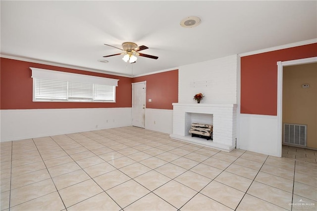 unfurnished living room with a fireplace, light tile patterned floors, ceiling fan, and ornamental molding