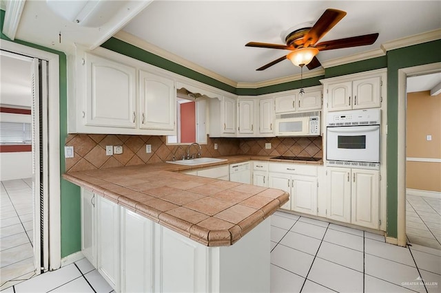 kitchen with kitchen peninsula, white appliances, and white cabinetry