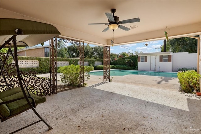 view of pool with a patio area, ceiling fan, and an outbuilding