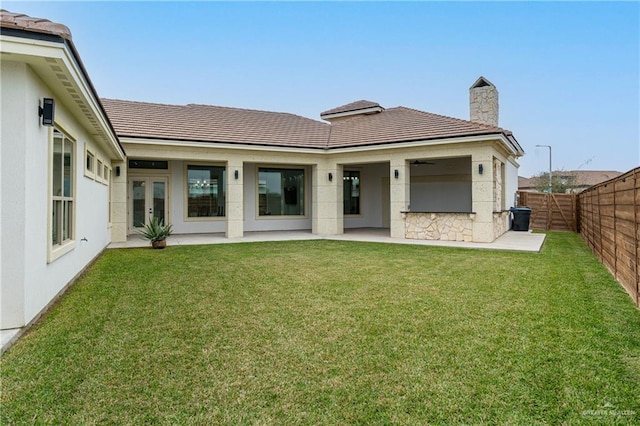 rear view of property featuring a patio area, a fenced backyard, a tile roof, and a lawn