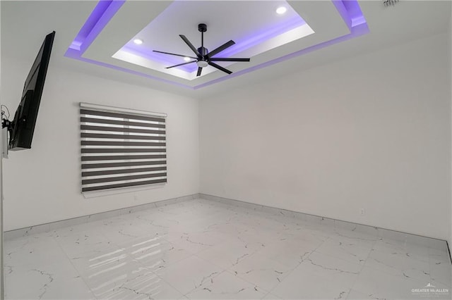 spare room featuring baseboards, ceiling fan, marble finish floor, a tray ceiling, and recessed lighting