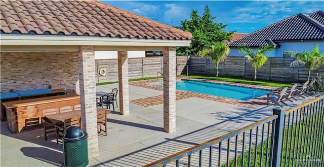 view of swimming pool featuring outdoor dry bar, a patio, a fenced backyard, and a fenced in pool