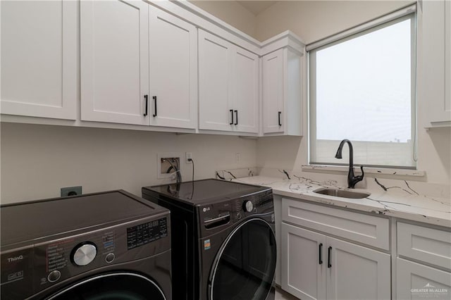 washroom with cabinet space, a sink, and separate washer and dryer