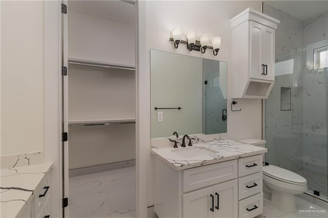 full bath featuring marble finish floor, a marble finish shower, a walk in closet, and vanity