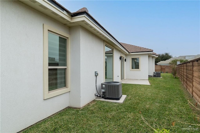 exterior space featuring cooling unit, a fenced backyard, a yard, and stucco siding