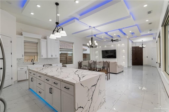 kitchen featuring pendant lighting, marble finish floor, open floor plan, white cabinetry, and a kitchen island