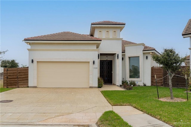 mediterranean / spanish-style home with stucco siding, an attached garage, fence, driveway, and a front lawn