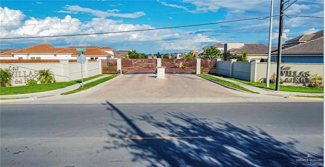 view of street featuring a residential view, a gate, curbs, and sidewalks