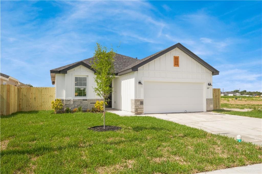 2217 Cardinal Dr, Weslaco, TX 78596 - view of front of home featuring concrete driveway, an attached garage, stone siding, board and batten siding, and roof with shingles