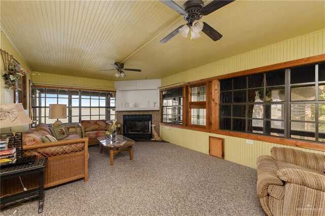 carpeted living room with ceiling fan and a large fireplace