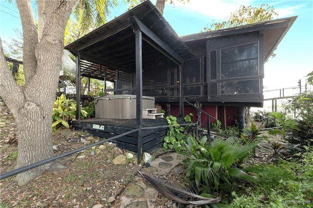 view of side of property featuring a hot tub and a sunroom