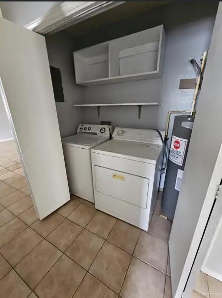 laundry room featuring water heater, light tile patterned floors, and washer and dryer