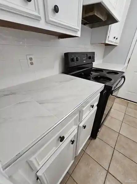 kitchen featuring white cabinetry, electric range, light tile patterned floors, and exhaust hood