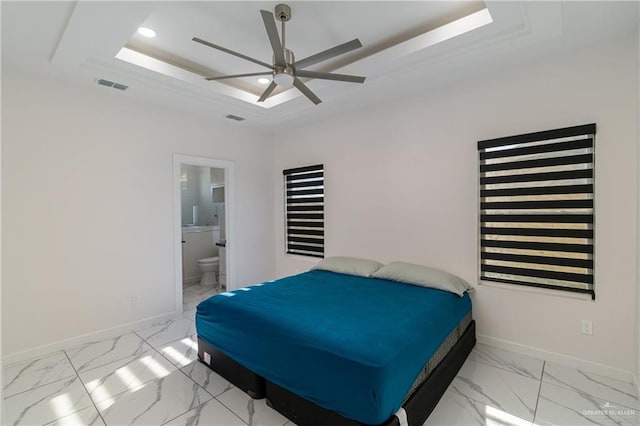 bedroom with a tray ceiling, ceiling fan, and ensuite bathroom