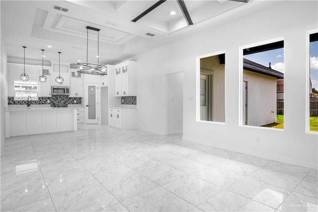 1506 N Rockport St, Alton, TX 78573 - kitchen with stainless steel microwave, light countertops, decorative backsplash, white cabinetry, and pendant lighting