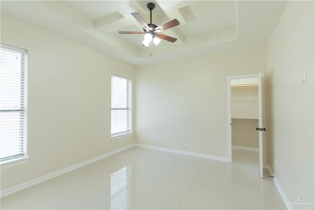 tiled spare room featuring plenty of natural light, ceiling fan, and a tray ceiling