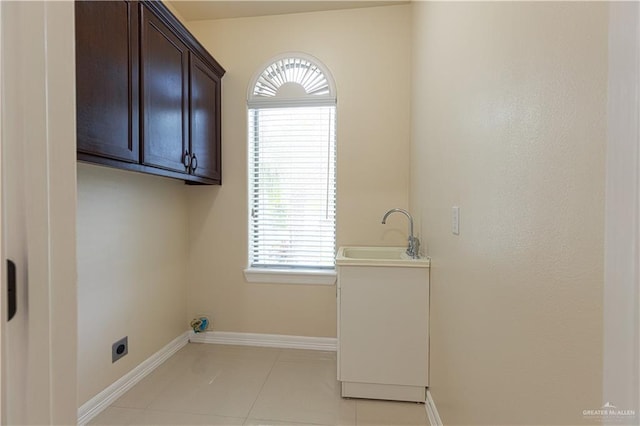 clothes washing area featuring sink, light tile patterned floors, a healthy amount of sunlight, and hookup for an electric dryer