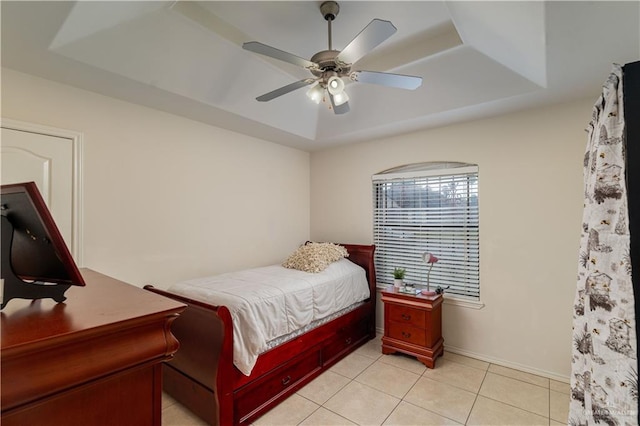 tiled bedroom featuring ceiling fan and a tray ceiling