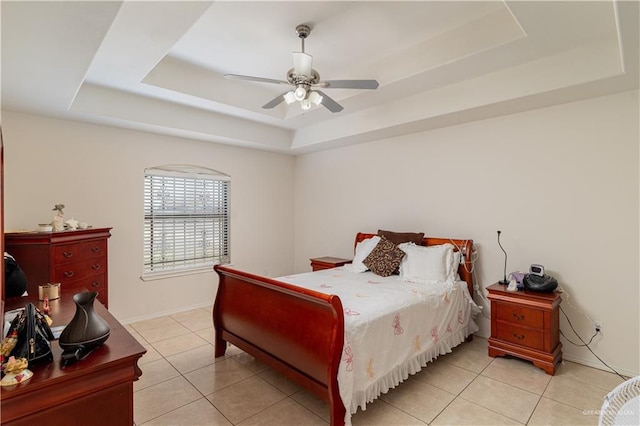 bedroom with light tile patterned flooring, ceiling fan, and a tray ceiling