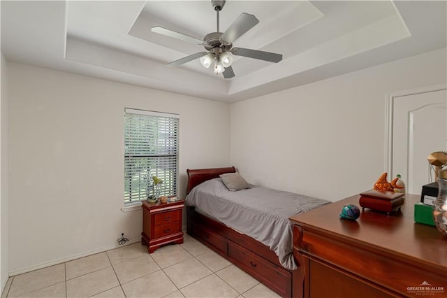 tiled bedroom with a raised ceiling and ceiling fan