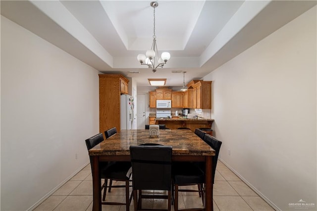 dining area with a raised ceiling, light tile patterned flooring, and a chandelier