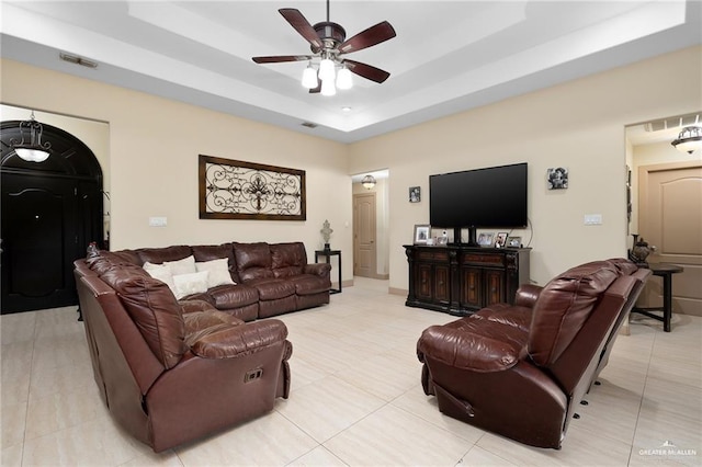 living room featuring ceiling fan, light tile patterned floors, and a tray ceiling