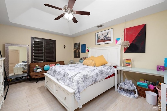 bedroom with a tray ceiling, ceiling fan, and light tile patterned floors