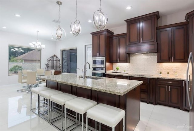 kitchen with a center island with sink, decorative light fixtures, sink, and stainless steel appliances