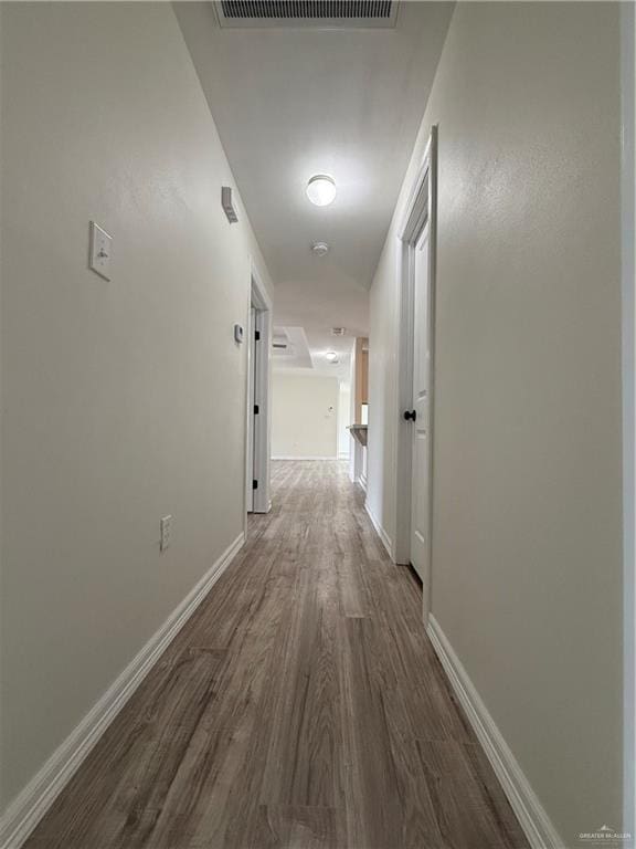 hall featuring wood finished floors, visible vents, and baseboards