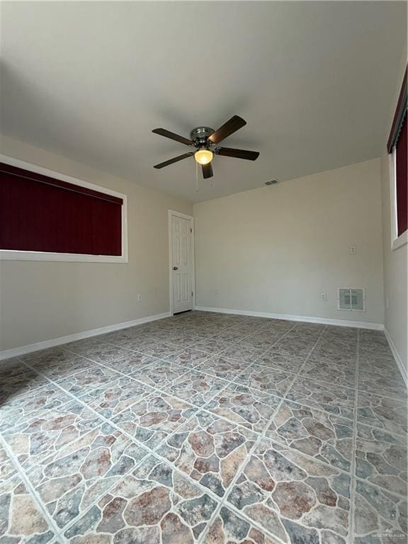 spare room with ceiling fan, visible vents, and baseboards