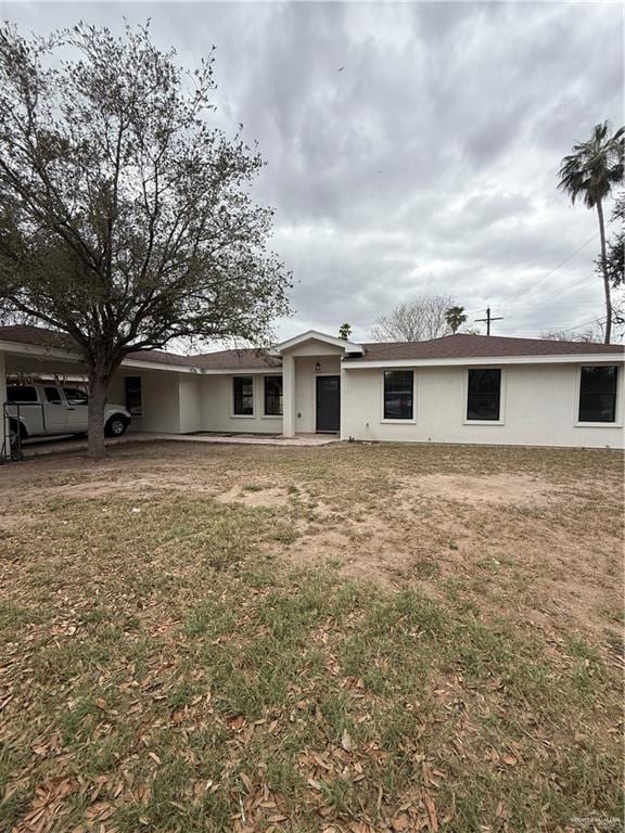 rear view of property with a lawn and stucco siding