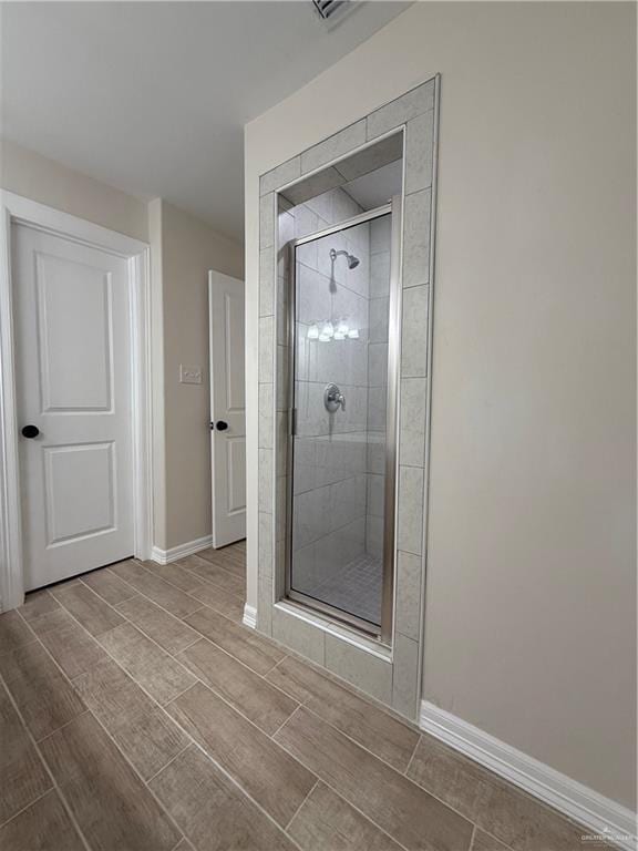 bathroom with a stall shower, baseboards, and wood tiled floor