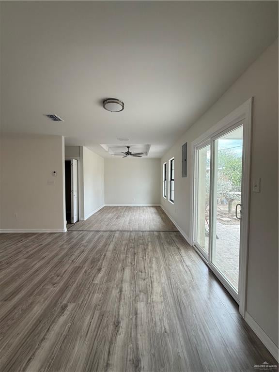 unfurnished living room with a ceiling fan, visible vents, baseboards, and wood finished floors