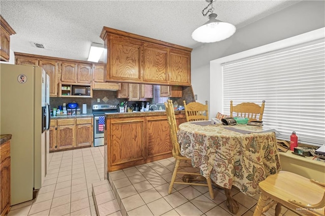 kitchen with backsplash, white refrigerator with ice dispenser, pendant lighting, light tile patterned floors, and stainless steel range with electric cooktop