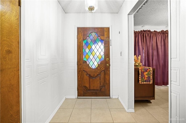 foyer entrance with a textured ceiling and light tile patterned flooring