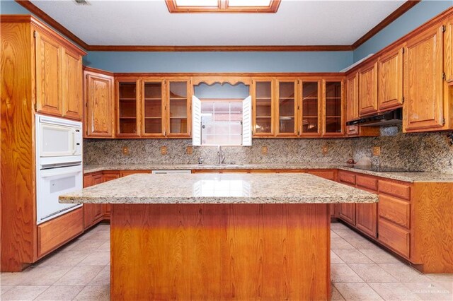 kitchen featuring white microwave, crown molding, sink, and a kitchen island