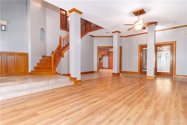 unfurnished living room featuring ceiling fan, light hardwood / wood-style floors, crown molding, and a high ceiling