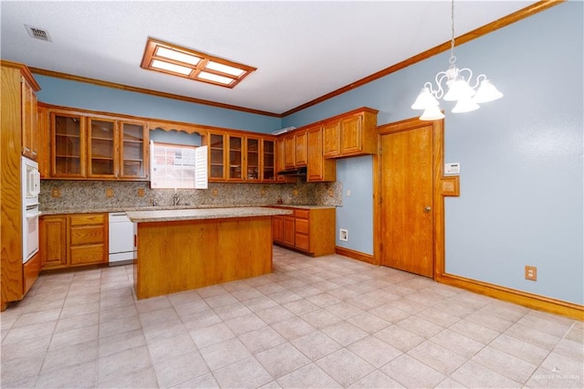 kitchen with a center island, a notable chandelier, pendant lighting, white appliances, and ornamental molding