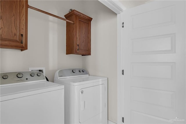 clothes washing area with cabinets and separate washer and dryer