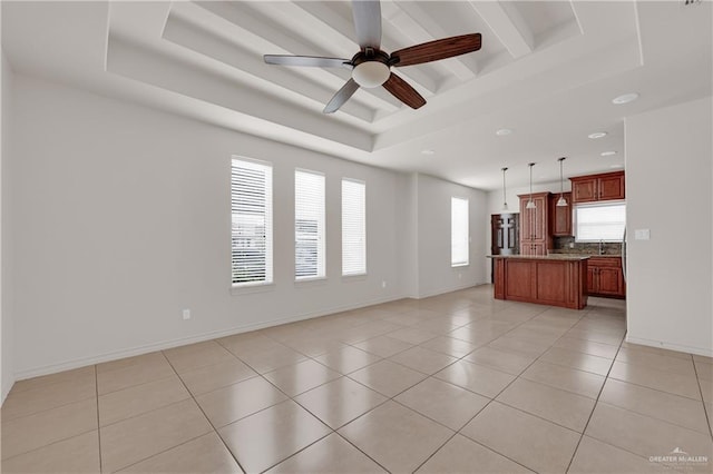 unfurnished living room with sink, ceiling fan, beam ceiling, a tray ceiling, and light tile patterned flooring